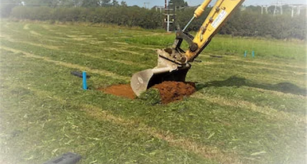 Excavator digging up a section of field